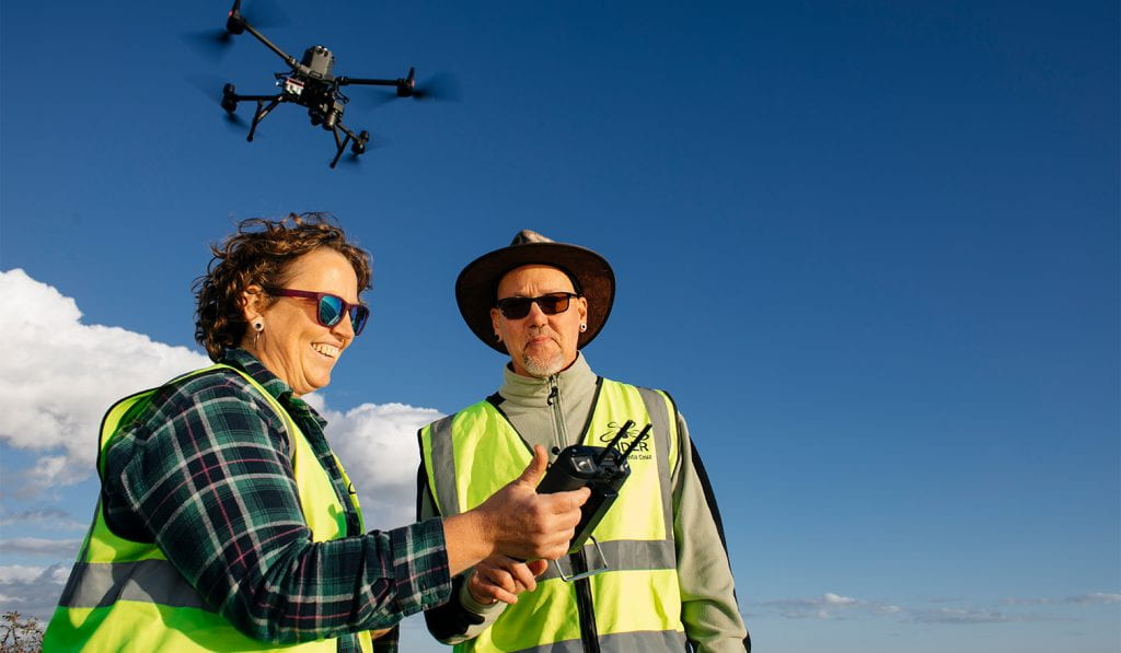 Two people operate drone outside