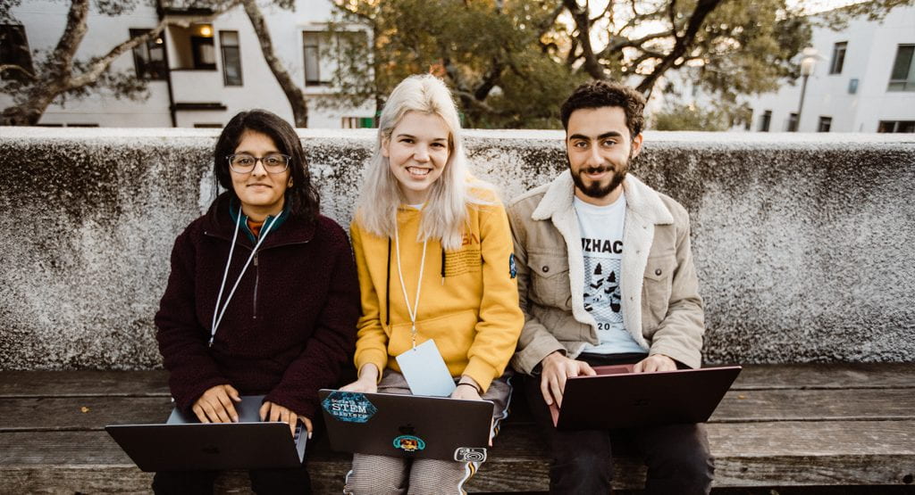 Three students work on laptops